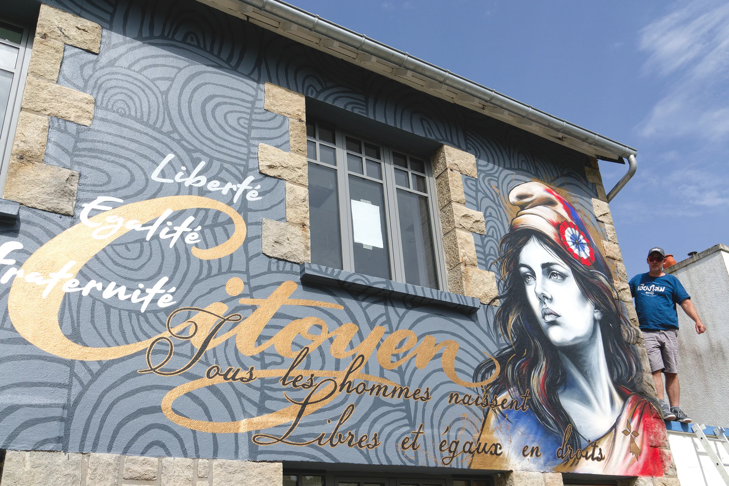 Le street artiste Morlaisien Gwendal Larher devant son portrait de la Marianne à trémel
