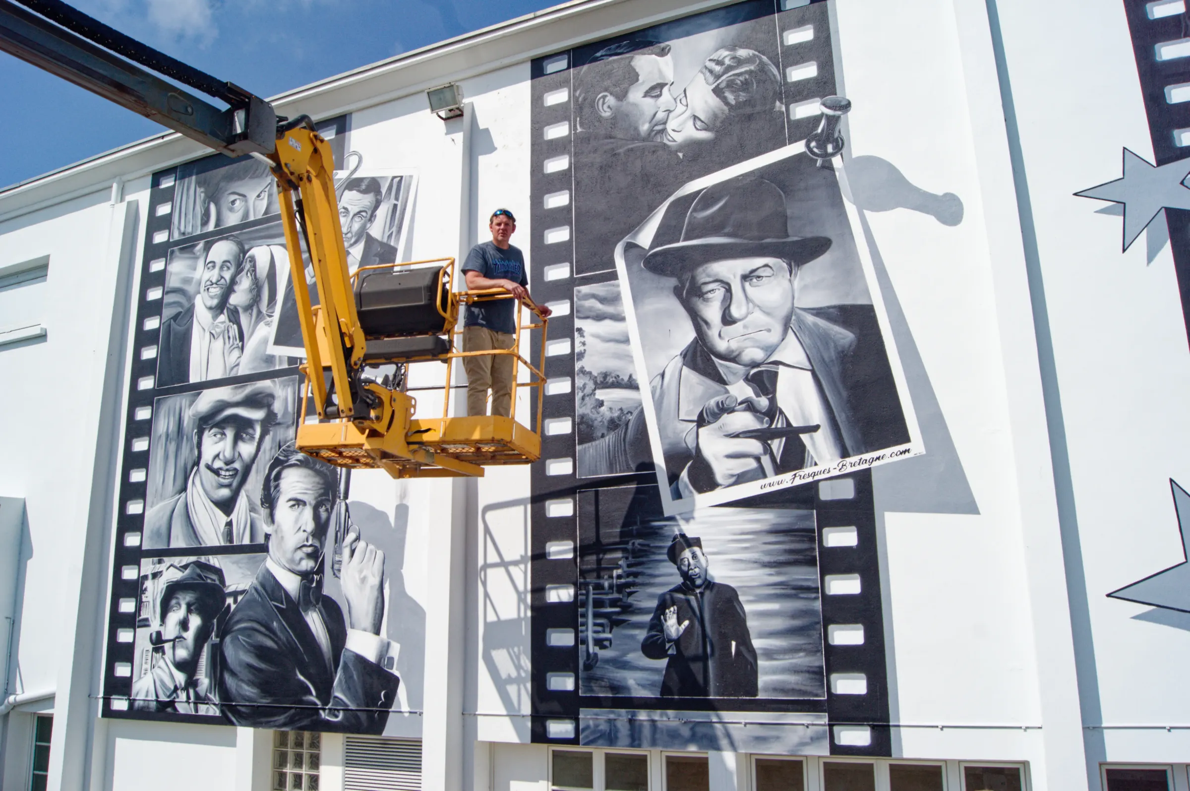Gwendal Larher artiste graffeur Morlaisien devant la fresque des acteurs au cinéma de Plouescat