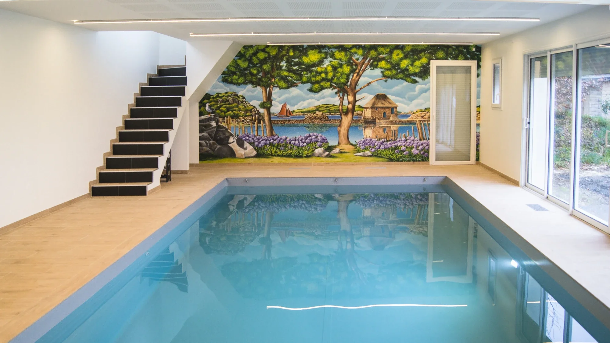 Piscine intérieure à Paimpol après réalisation : moulin à marée et voilier en trompe-l'œil, décor immersif résistant à l'humidité